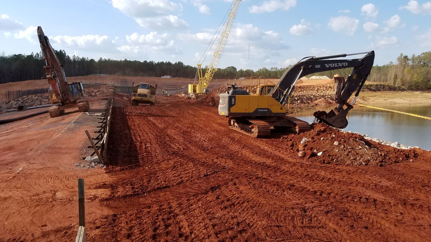 Excavators and a crawler crane working around formed concrete walls.