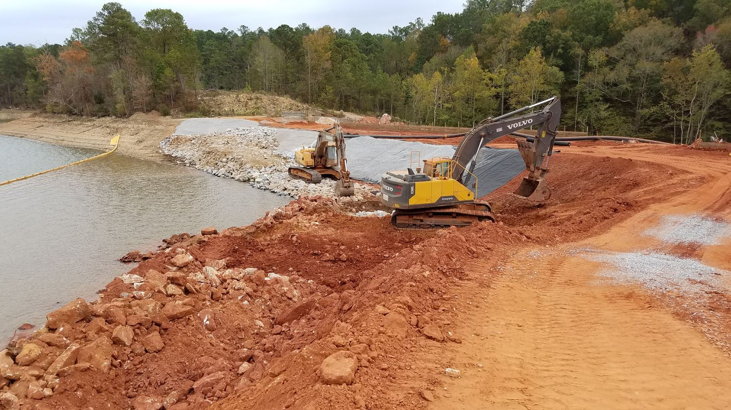 Two excavators working rock and fabric along the reservoir bank.