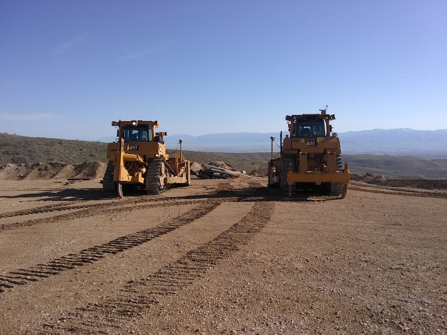 Two CAT dozers parked with hazy valley behind.