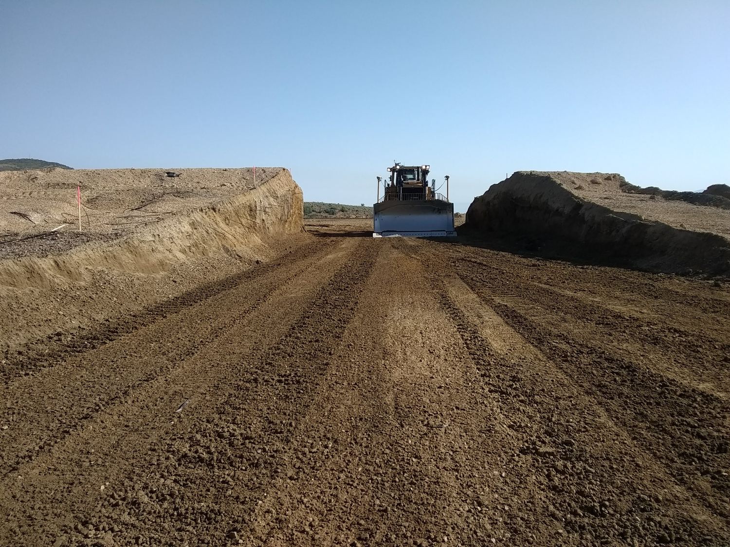 Dozer framed dead-center in a graded road cut.