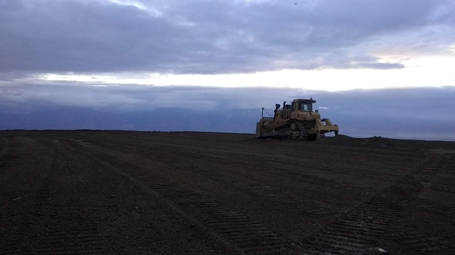 Dozer silhouette against a clouded evening sky.