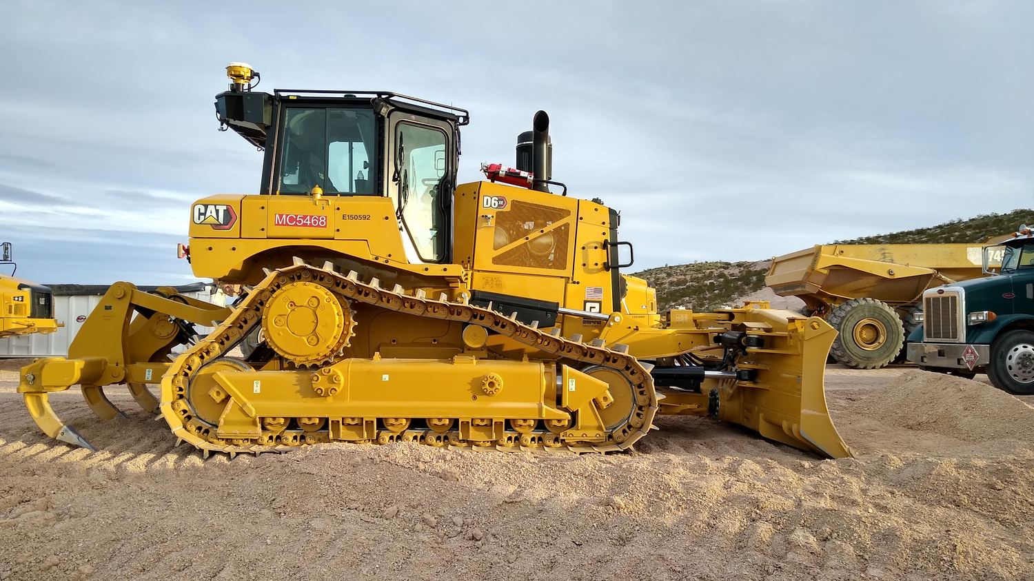 CAT D6 XE dozer with root rake and ripper, haul truck staged behind.