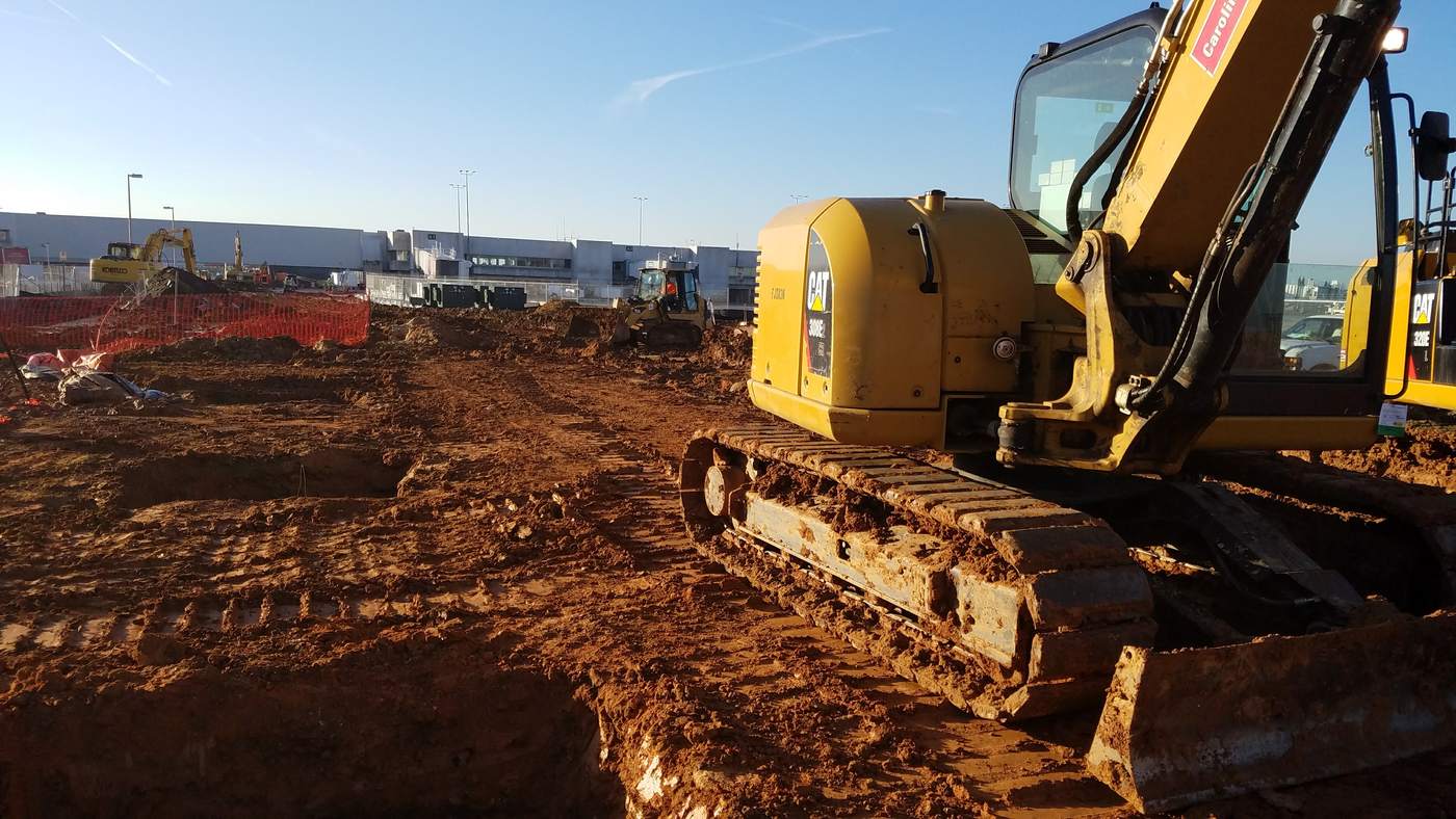 Excavators working alongside an airport terminal building during expansion work.