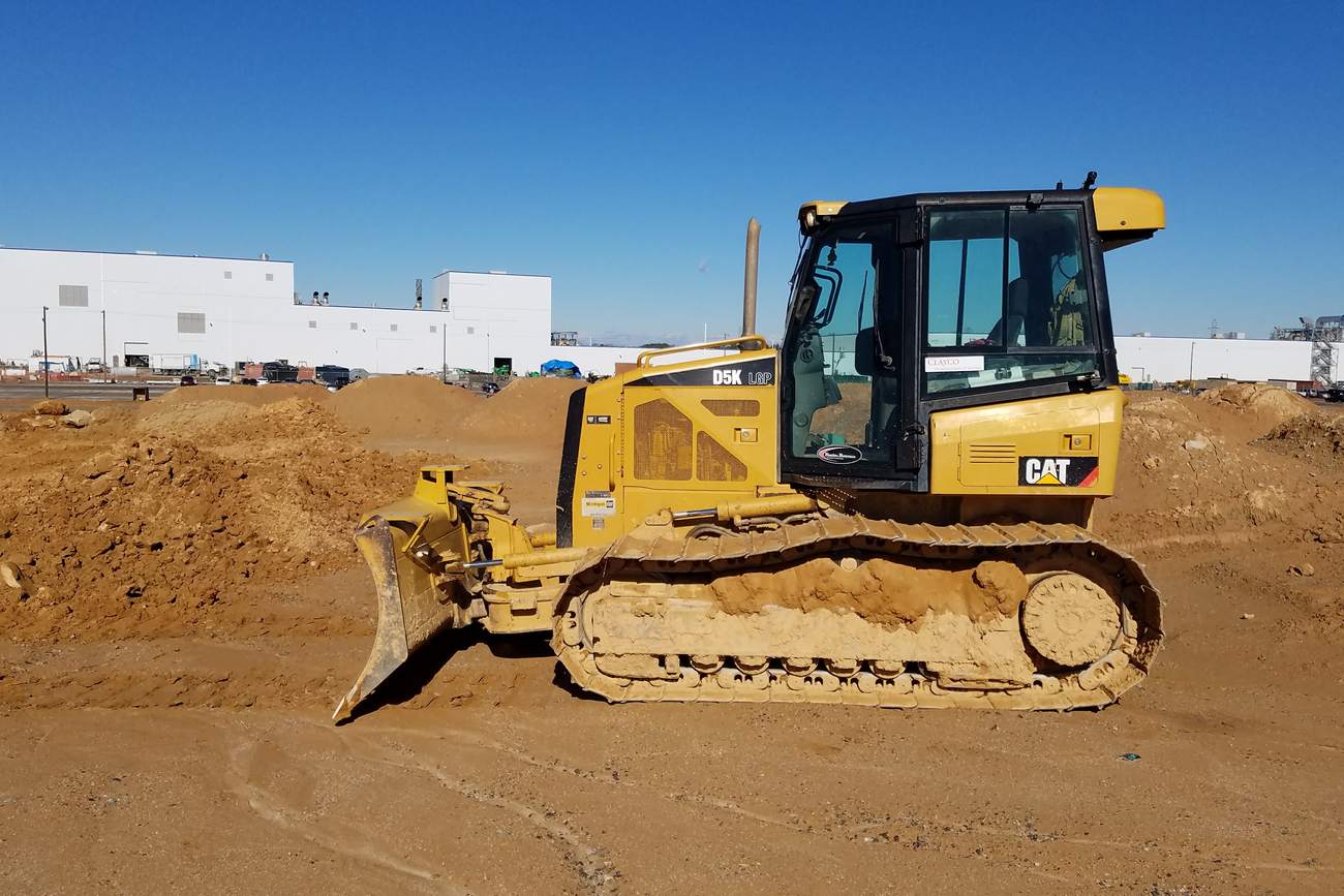 Cat D5K LGP dozer at an industrial plant construction site.