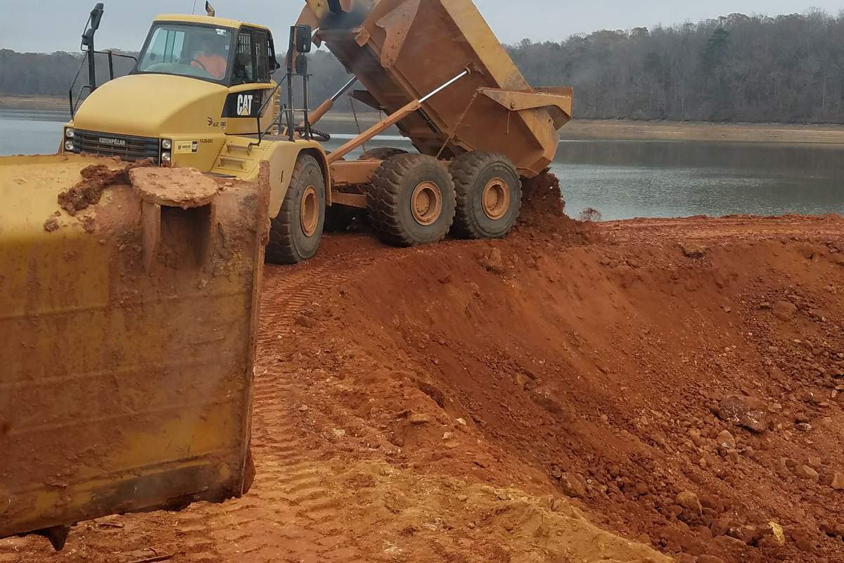 Articulated haul truck dumping fill at the water line on a reservoir project.