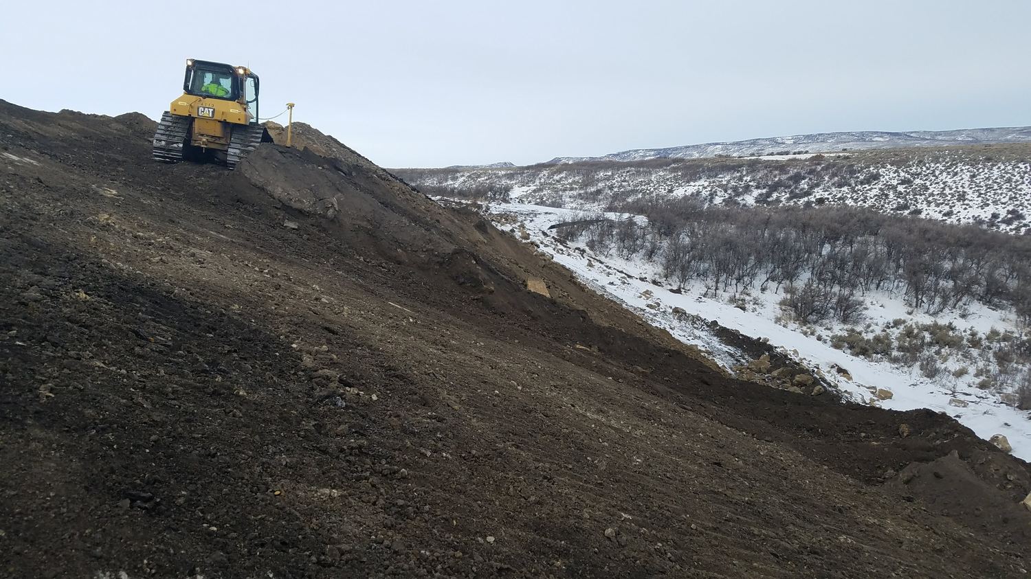 Dozer cutting a bench above a valley at the Climax Mine.
