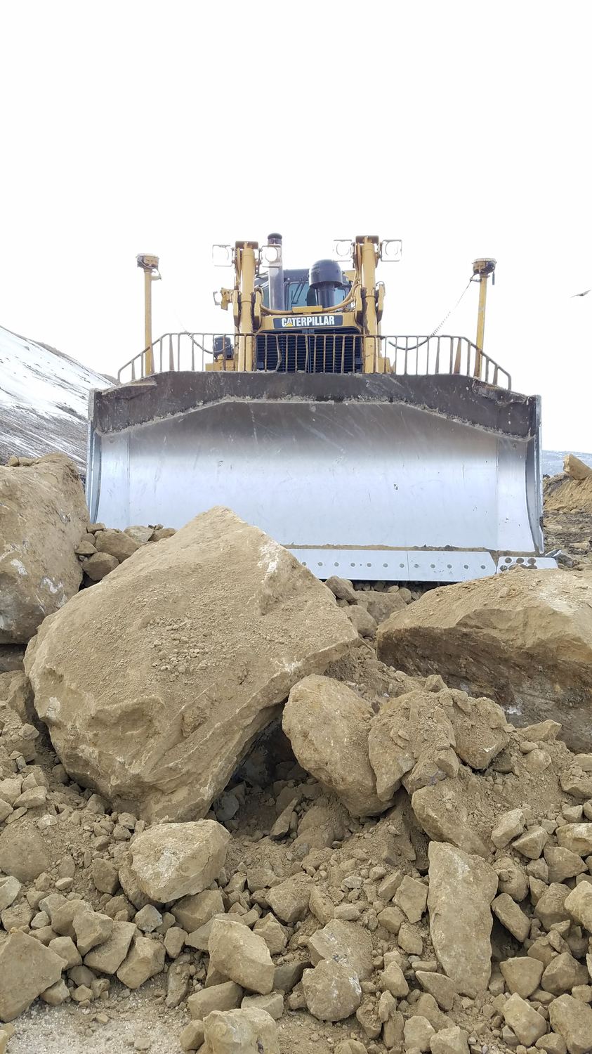 Dozer blade nose to nose with large boulders.