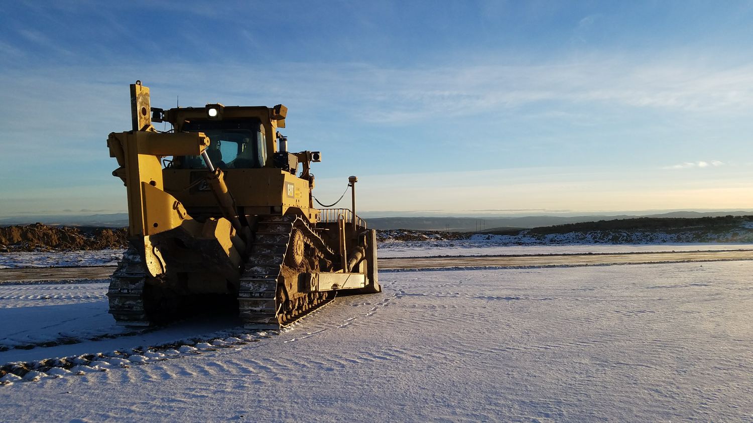 Dozer holding grade on a broad snow-covered bench.