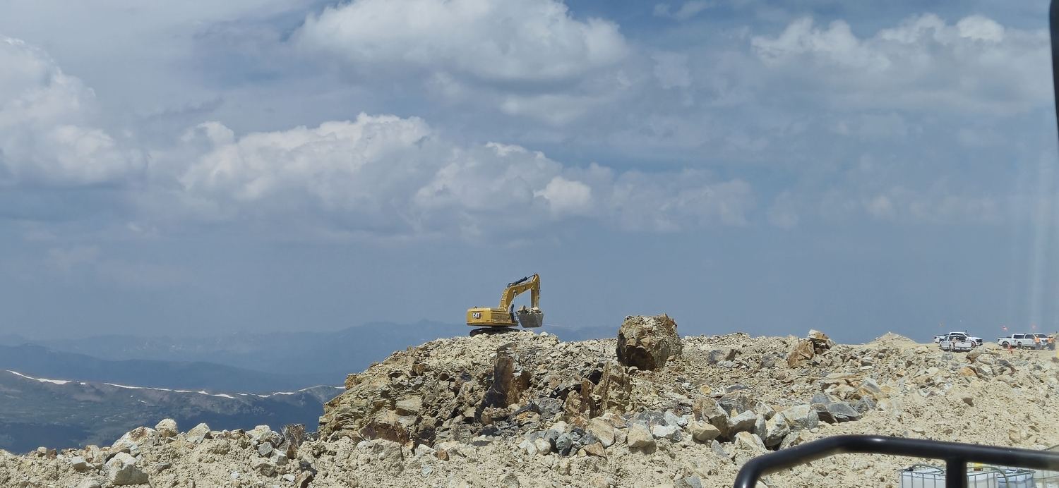 Excavator working alone along a high ridge.