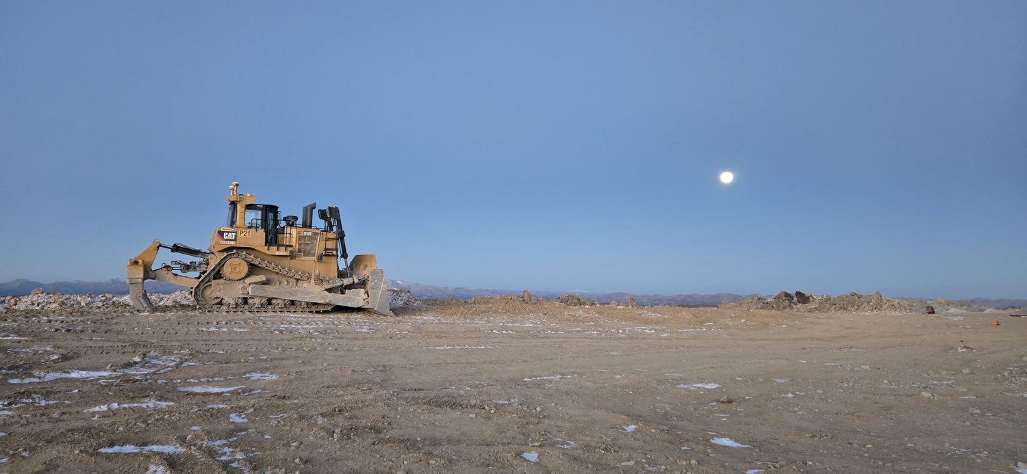 CAT D10T dozer under a rising moon at dusk.