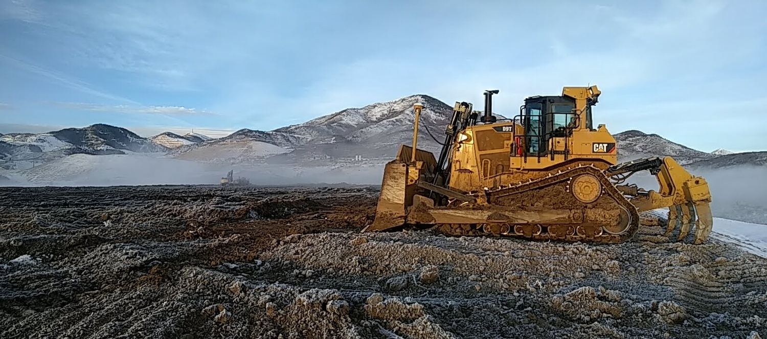 CAT D9T dozer working frosted ground at dawn.