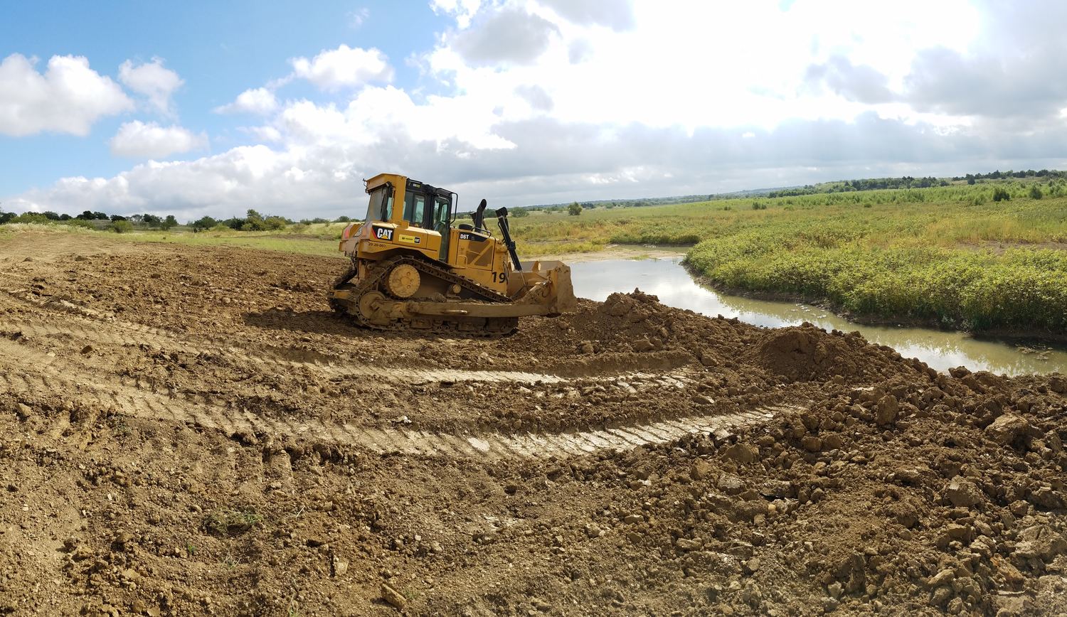 CAT D6T shaping the bank beside a spillway channel.