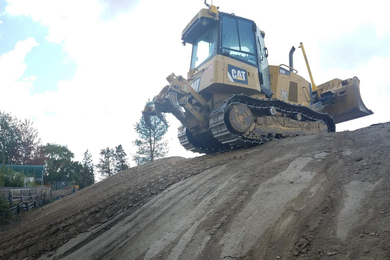 Cat dozer working the crest of a steep fill slope.