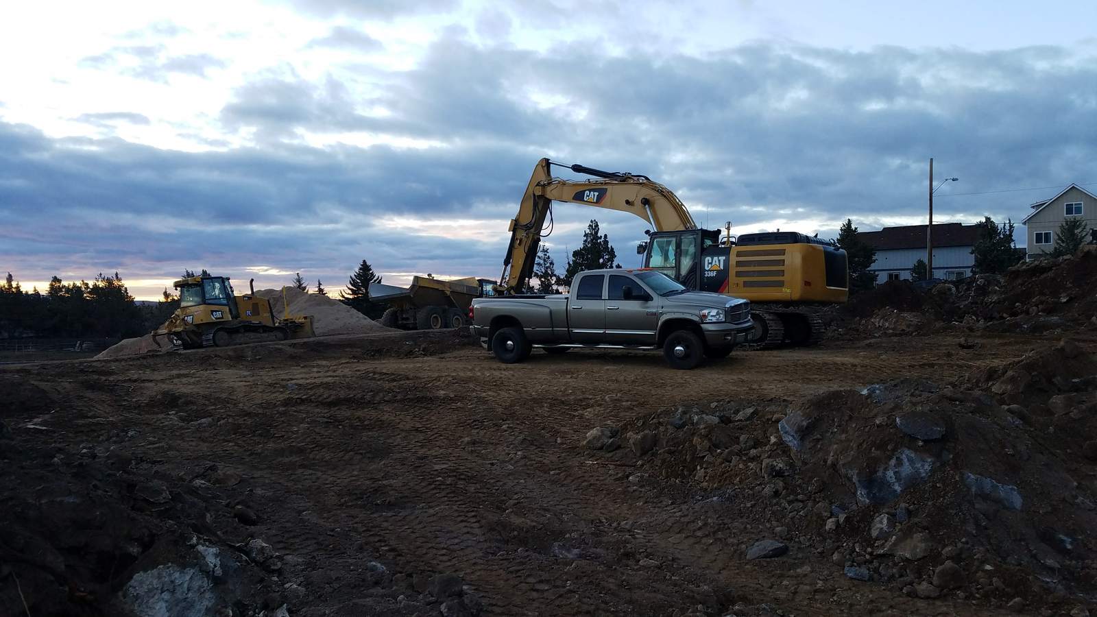 Excavator, articulated truck and dozer on a central Oregon site at dusk.