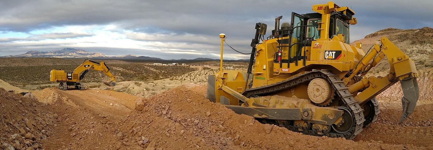 CAT dozer and excavator working a bench, desert range behind.