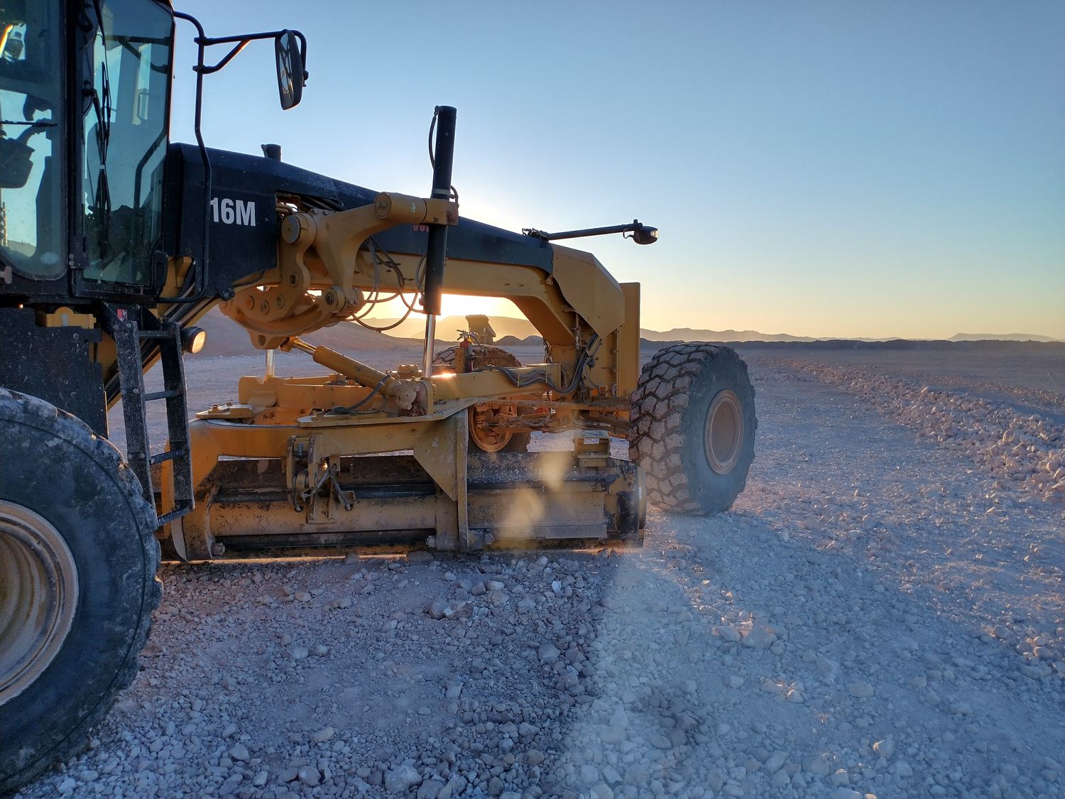 Excavator swinging a load between two haul trucks.