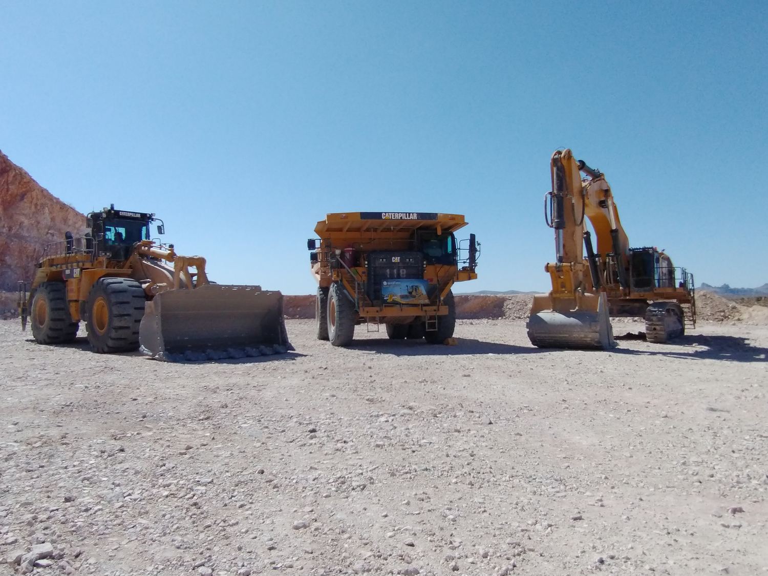 A line of haul trucks queued at first light, loader working the face beyond.